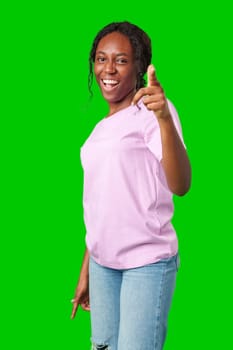 Young woman in a pink shirt playfully pointing fingers at the camera against a bright green background in studio