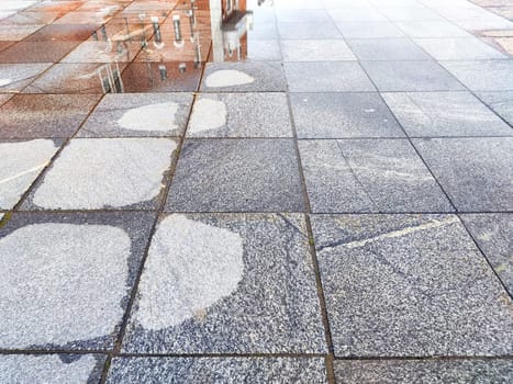 Rain-soaked pavement reflects nearby buildings and creates a serene urban environment in the aftermath of a rain shower.