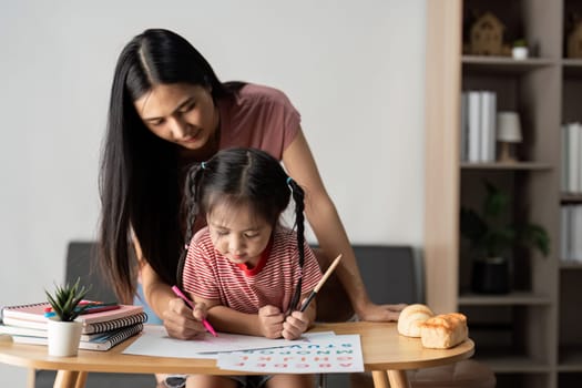 A mother and daughter enjoying a creative learning session at home, surrounded by art supplies and books.