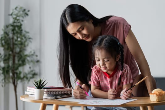 A mother and daughter engage in a fun drawing activity at home, fostering creativity and bonding in a cozy living room environment.