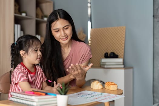 A mother and daughter engage in a fun learning activity at home, fostering education and bonding in a comfortable living room environment.
