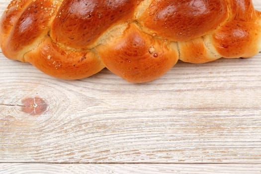 Golden, braided challah bread beautifully resting on a rustic wooden table, perfect for every celebration or meal