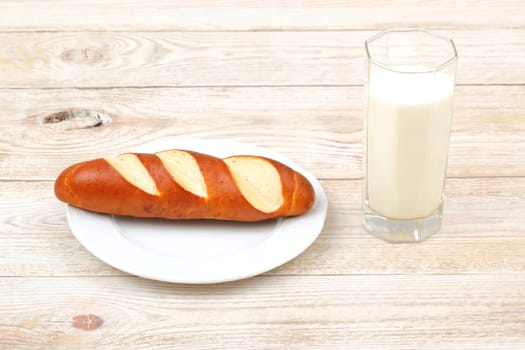 A perfectly freshly baked breadstick accompanied by a cold glass of milk on a rustic wooden dining table