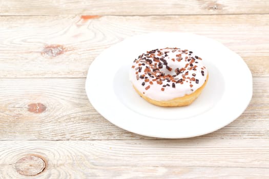 A deliciously tempting doughnut that is generously topped with colorful chocolate sprinkles on a bright white plate
