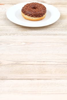 A very delicious chocolate donut topped generously with colorful sprinkles, artfully placed on a pristine white plate