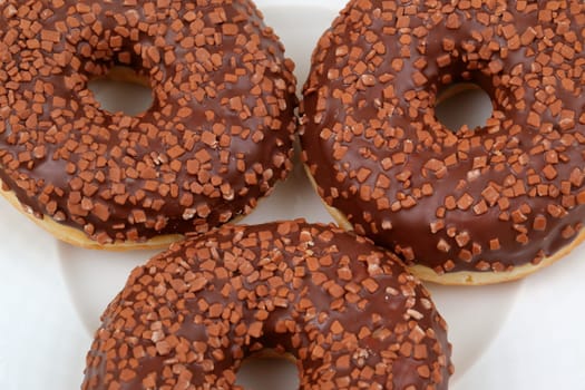Indulge in a tempting trio of luscious chocolatecovered donuts, beautifully topped with vibrant and crunchy sprinkles