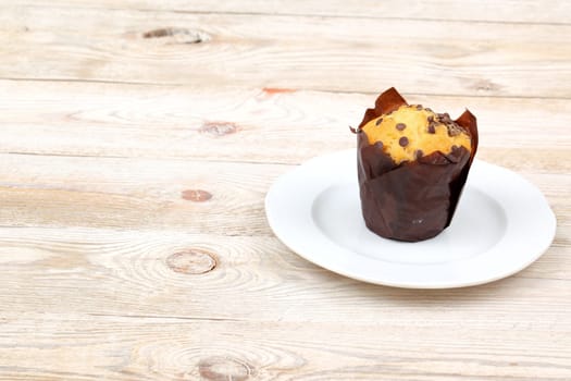 A truly scrumptious chocolate chip muffin presented elegantly on a pristine white plate ready for enjoyment