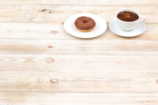 In a cozy and inviting scene, a delicious chocolate donut pairs perfectly with steaming coffee on a rustic wooden table