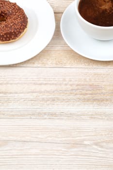 Enjoy a hot cup of coffee with a fresh chocolate donut, elegantly presented on a rustic wooden table