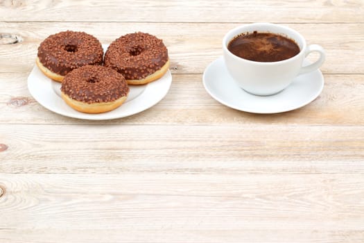Take pleasure in a delightful and cozy moment savouring chocolate donuts and fresh coffee on a rustic wooden table