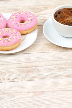 Deliciously sweet pink donuts perfectly paired with a warm cup of coffee, ideal for breakfast or a delightful snack