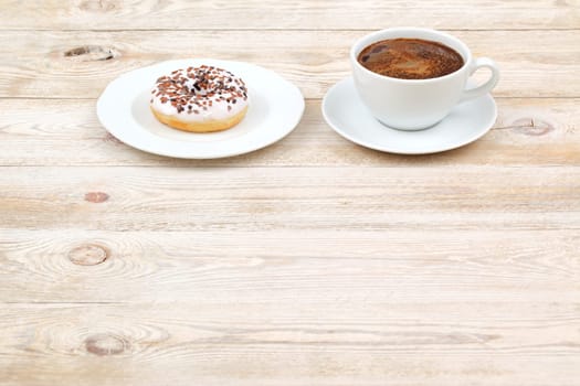 A delightful and perfect pairing of rich coffee and a sweet donut placed on a rustic wooden table surface