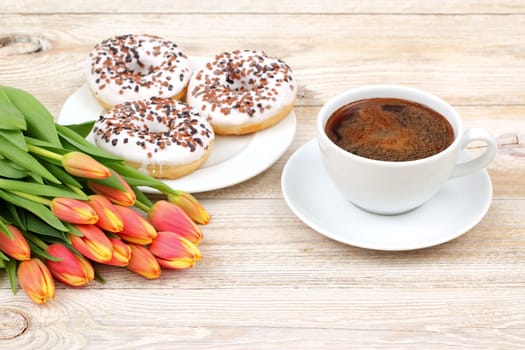 Take some time to enjoy a cozy moment filled with aromatic coffee, colorful donuts, and fresh tulip flowers