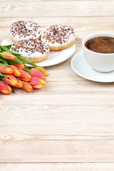 A scene with a steaming cup of coffee, tasty donuts, and bright tulips, perfect for spring mornings