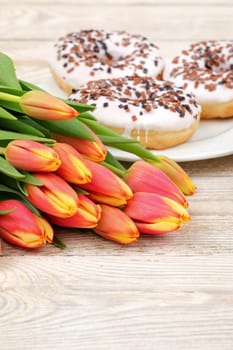 A vibrant bouquet of colorful tulips paired with tempting donuts, creating a perfect atmosphere for a cheerful setting