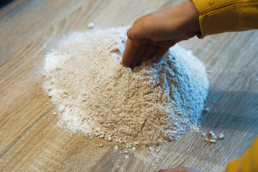 baby child kid hand making hole in flour hill help cooking family quality time together kitchen home. High quality photo