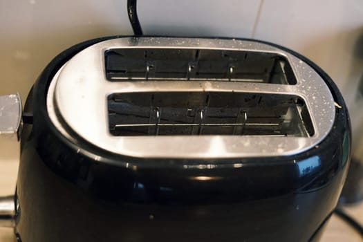 black modern toaster with bread crumbs on home kitchen authentic breakfast equipment . High quality photo