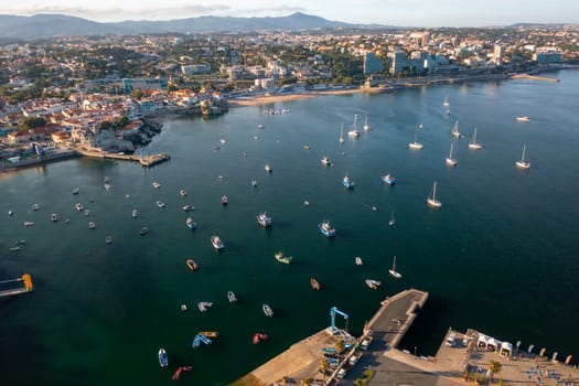 Aerial drone panning over crowded cityscape and Cascais marina in Portugal. From above view of residential area on coast of harbor during sunny day