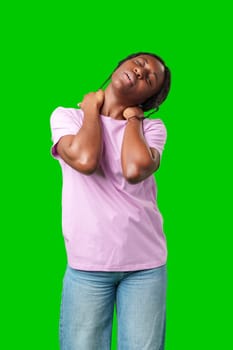 Young woman experiencing neck pain against a bright green background in studio
