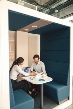 Two business colleagues working together with financial statements in stylish meeting room