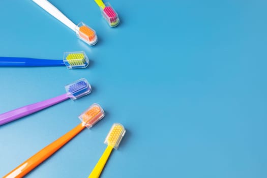 Flat Lay Few of Multicolored Toothbrushes Lying in Shape Of Sun On Blue Background, Space For Tex. Morning hygiene, Bathroom accessories. Dental Health Care. Horizontal Top View Plane.