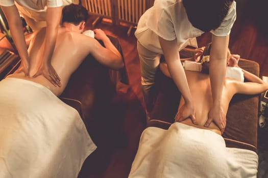 Top view couple customer enjoying relaxing anti-stress spa massage and pampering with beauty skin recreation leisure in warm candle lighting ambient salon spa at luxury resort or hotel. Quiescent