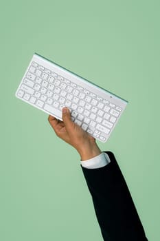 Hand holding wireless keyboard on isolated background for start up tech company. Eco-friendly green business promoting electronic waste policy idea. Quaint