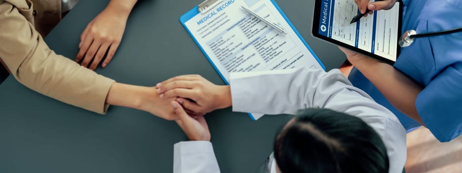 Doctor show medical diagnosis report and providing compassionate healthcare consultation, holding young patient hand for being supportive and professional in doctor clinic office. Top view Neoteric