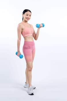 Vigorous energetic woman doing dumbbell weight lifting exercise on isolated background. Young athletic asian woman strength and endurance training session as body workout routine.