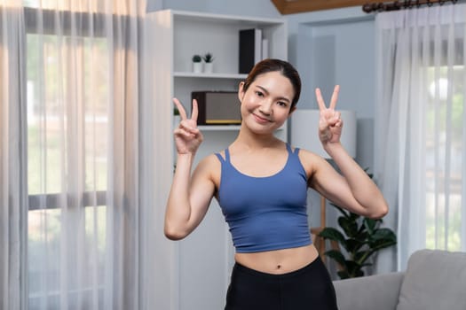 Asian woman in sportswear portrait, smiling and posing cheerful gesture. Home workout training or exercise fitness lifestyle. Attractive girl engage in her pursuit of healthy lifestyle. Vigorous