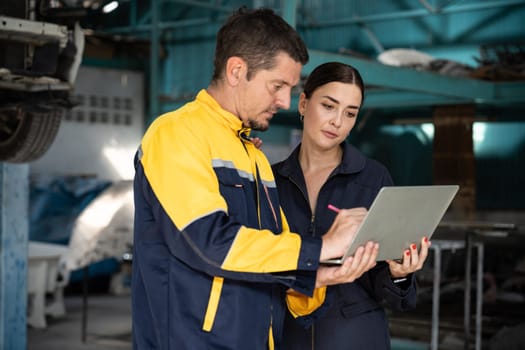 Two vehicle mechanic working together, conduct car inspection with laptop. Automotive service technician in uniform carefully make diagnostic troubleshooting to identify error. oxus