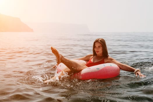 Woman summer sea. Happy woman swimming with inflatable donut on the beach in summer sunny day, surrounded by volcanic mountains. Summer vacation concept