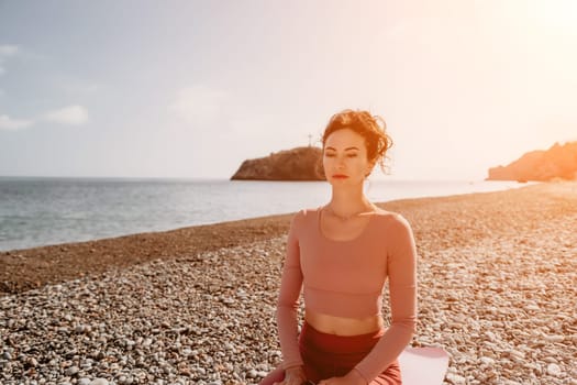 Middle aged well looking woman with black hair doing Pilates with the ring on the yoga mat near the sea on the pebble beach. Female fitness yoga concept. Healthy lifestyle, harmony and meditation.