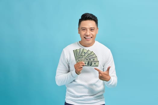 happy man with money fan, standing isolated against blue background