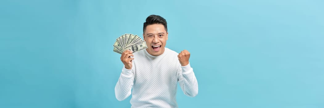 happy man with money fan, standing isolated against blue banner