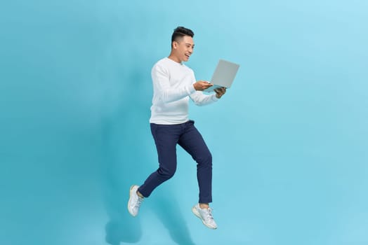 young man run jump hold laptop agent marketer isolated over blue background