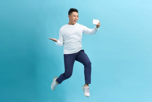 Asian man jumping and holding smartphone , isolated on blue