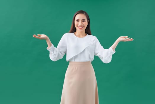 smiling beautiful young woman showing copyspace over green background