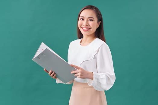 Portrait of a happy asian businesswoman holding clipboard isolated over green background