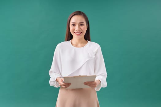 Beautiful business woman taking notes on her clipboard isolated on green background