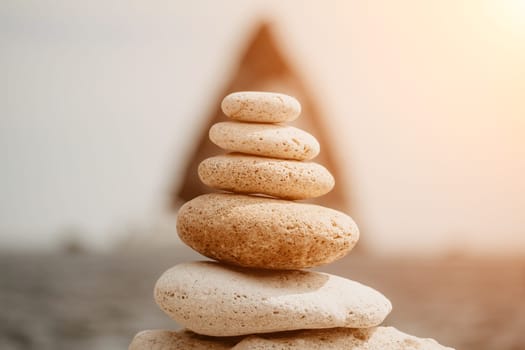 Pyramid stones on the seashore with warm sunset on the sea background. Happy holidays. Pebble beach, calm sea, travel destination. Concept of happy vacation on the sea, meditation, spa, calmness.