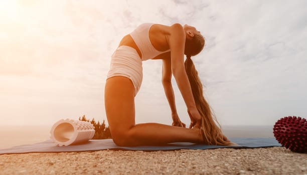 Middle aged well looking woman with black hair doing Pilates with the ring on the yoga mat near the sea on the pebble beach. Female fitness yoga concept. Healthy lifestyle, harmony and meditation.