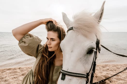 A woman in a dress stands next to a white horse on a beach, with the blue sky and sea in the background