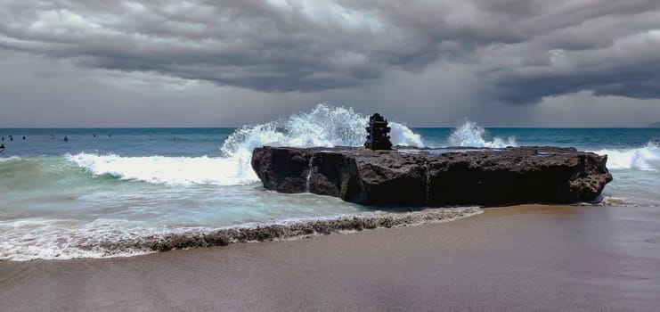 A Stormy Day this image depicts a dramatic and foreboding scene of a beach with a stormy sky and rough waves. The water is a deep blue color, contrasting with the dark and cloudy sky. The waves are crashing against a large rock formation in the center of the image, creating a sense of power and danger. The beach is sandy and deserted, adding to the lonely and gloomy mood of the image.a. High-quality photo