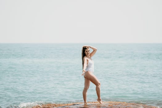 Woman sea yoga. Back view of free calm happy satisfied woman with long hair standing on top rock with yoga position against of sky by the sea. Healthy lifestyle outdoors in nature, fitness concept.