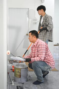 Two painters working on a painting project in an indoor space..