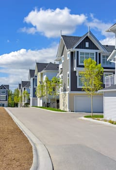 A perfect neighborhood. Brand new townhouses district on blue sky and clouds background.