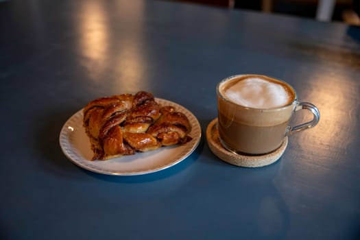 A close-up of a freshly baked cinnamon pastry served on a white plate. The warm, inviting lighting enhances its golden-brown texture, creating a cozy and appetizing atmosphere in denmark png file