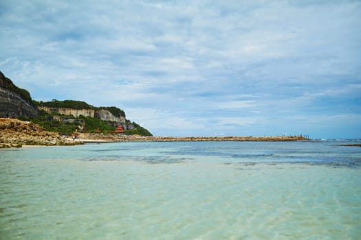 An incredibly beautiful deserted tropical beach under a cliff with clear, clean ocean water on the popular tourist island of Bali