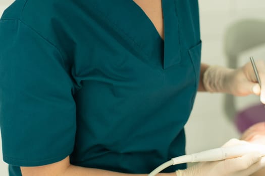 Dentist in gloves holding his tools during patient examination